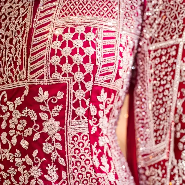 Close-up of golden zari and cut dana hand embroidery on hot pink wedding lehenga fabric