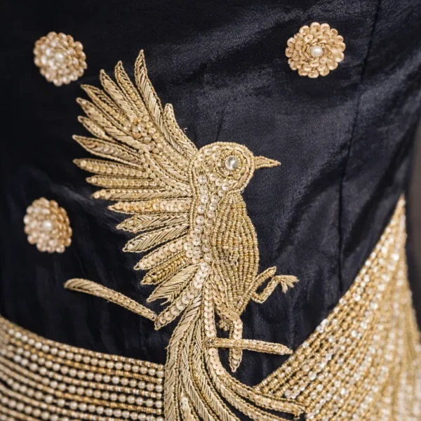 Close-up of gold zardosi and cut dana bird motif embroidery on black fabric